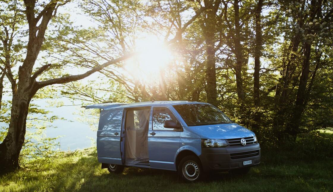 Bild von einem zum Camper ausgebauten Transporter am See.